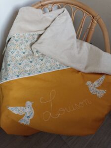 Sur fauteuil en osier sortie de bain brodée avec prénom et 2 oiseaux jaune moutarde et motifs fleurs